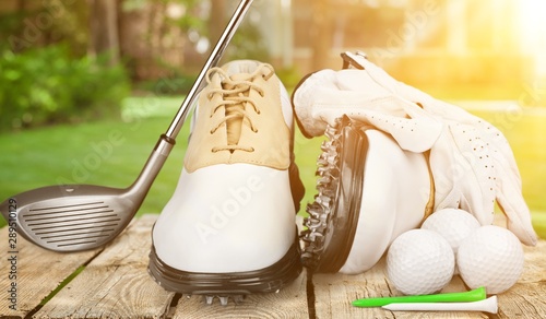 A pair of golfing shoes and a golf club on  background photo