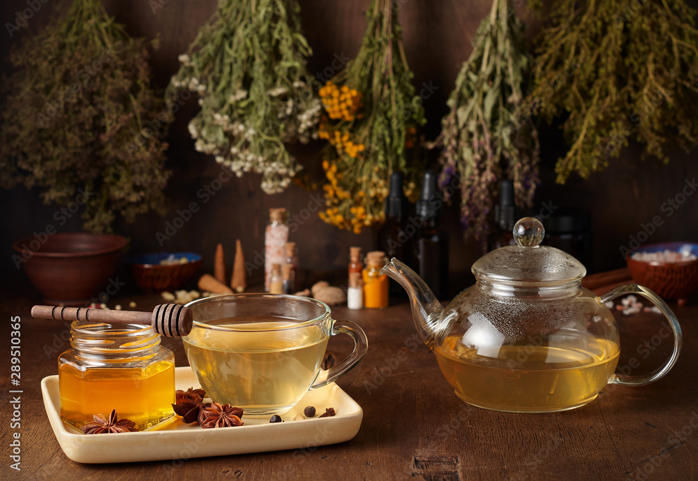 Cup of hot tea with honey, spices and drying medical herbs for use in alternative medicine