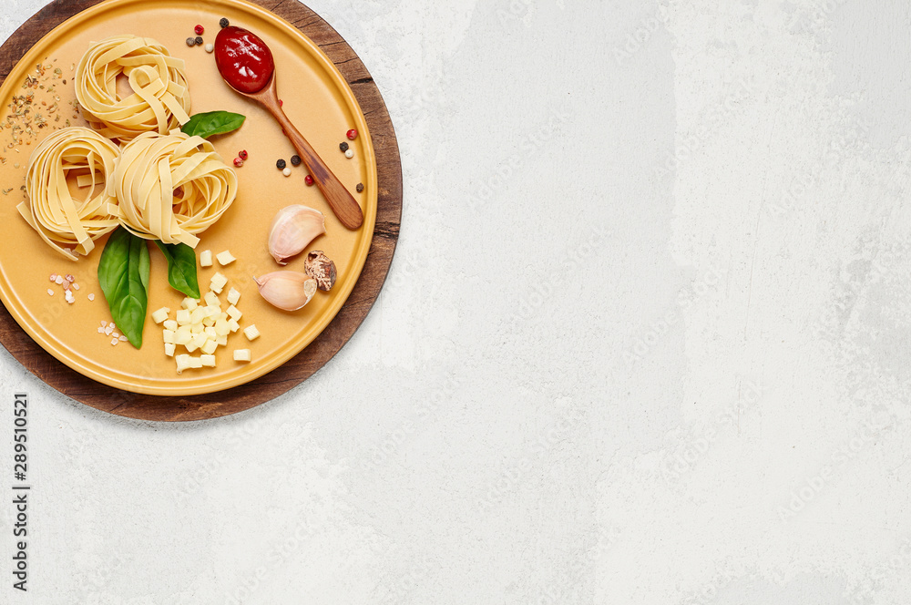 Ingredient for simple italian dinner on yellow plate. Fettuccine, fresh basil, tomato souce and mozzarella cheese