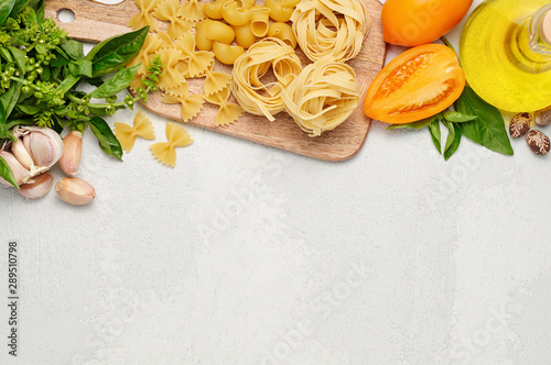 Different types of Italian pasta, fresh basil, olive oil, orange tomatoes and garlic