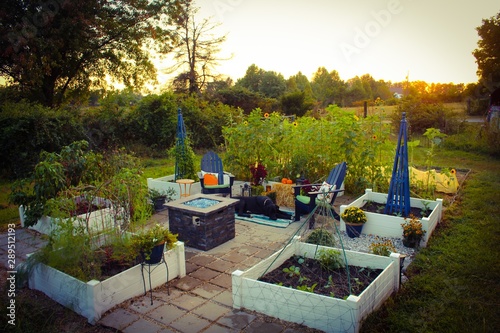 Outdoor patio and raised garden beds at sunset, decorated for Autumn with pumpkins, plants, hay bales, chrysanthemum and lanterns