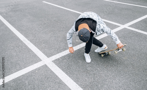 Teenager skateboarder boy with a skateboard on asphalt playground doing tricks. Youth generation Freetime spending concept image.