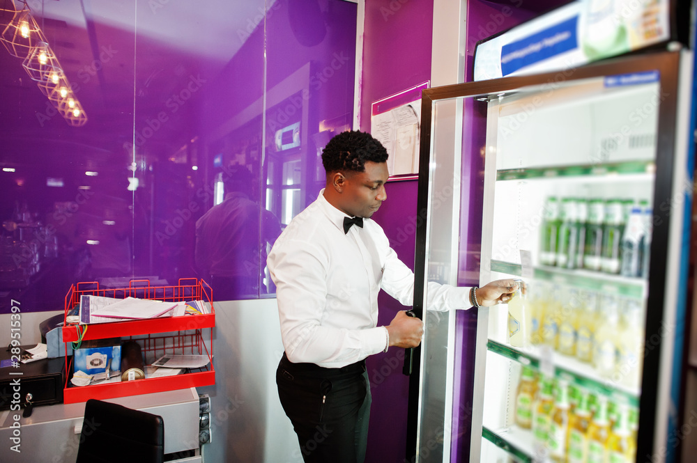 Fototapeta premium African american bartender at bar taking beer from fridge.