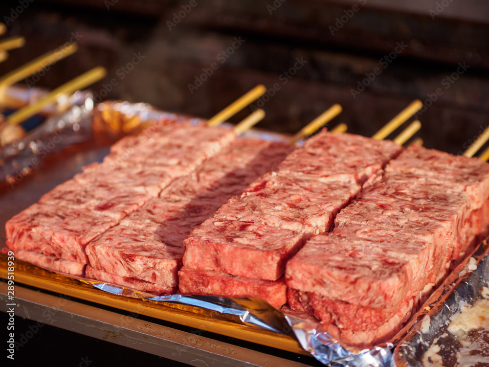 Closeup of raw beef on skewers at a Kushiyaki, grilled meats stand. Omiya, Saitama, Japan. Travel and street foods.
