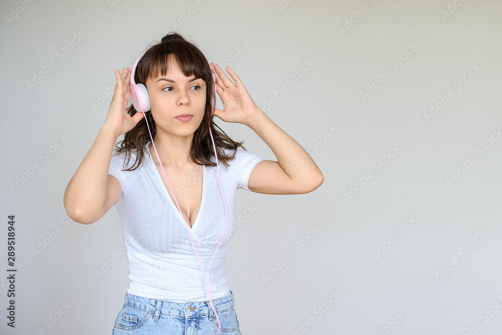 close up photo of a happy brunette with pink headphones in white blouse and denim skirt