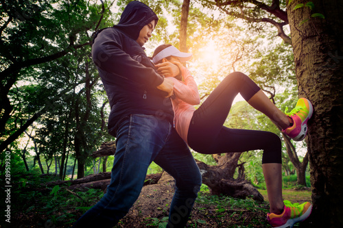 Fotografija young fighting with robber , woman attack robber in the forest alone