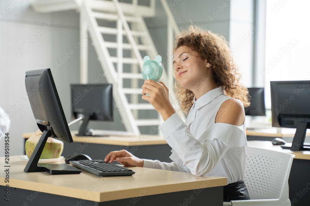 Businesswoman happiness in office with computer and fan cooling.funny in summer concept.