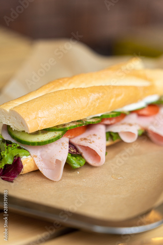 Sandwich on fresh french baguette with ham and vegetables close up photo