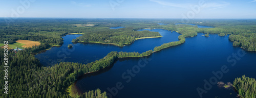Aerial panorama of blue lakes and green forests on a sunny summer day in rural Finland. Drone photography from the air.