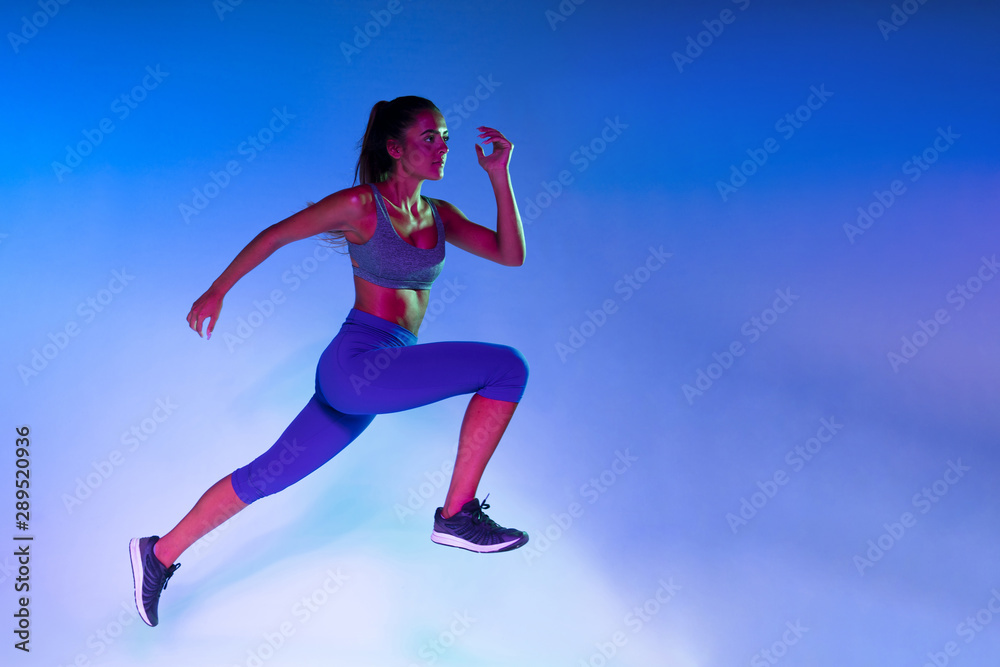 Side view of athlete training with blue background