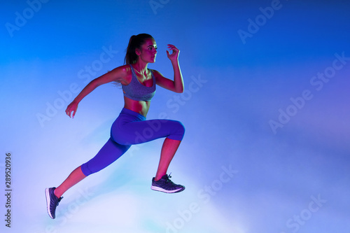 Side view of athlete training with blue background