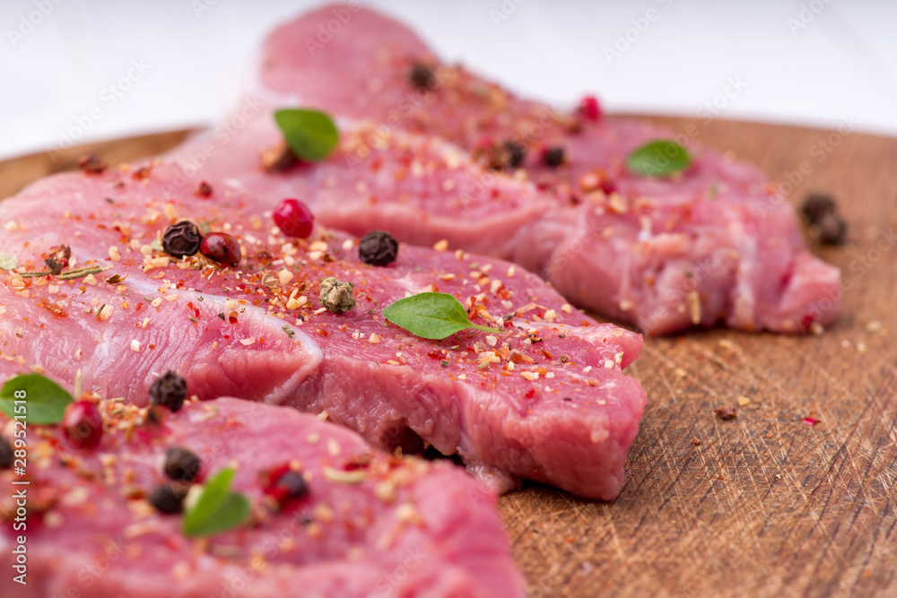 Raw pork steaks sprinkled with spices and herbs. Juicy raw steaks for a barbecue, close up. Raw pork steaks sprinkled with spices and herbs. Juicy raw steaks for a barbecue, close up.