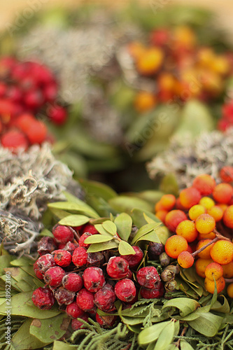 Bunter, natürlicher Beerenkranz mit grünen Blättern und roten Beeren, als Weihnachtsdekoration und Adventskranz.