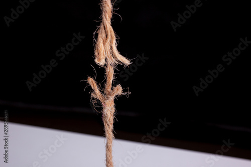 frayed rope ready to break on black background