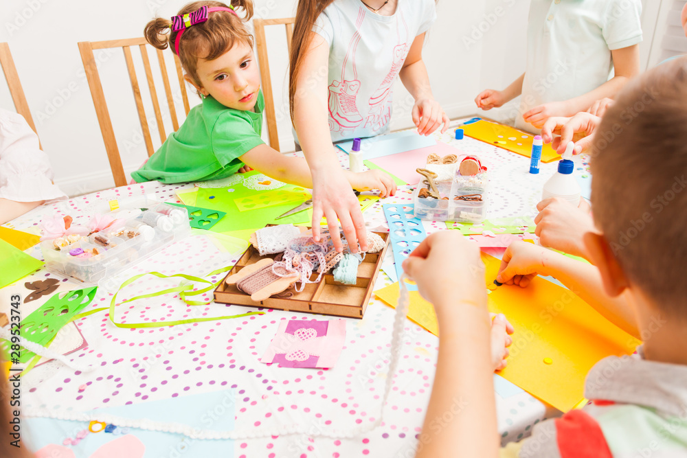 Fototapeta premium Little girl makes handicraft together with other children
