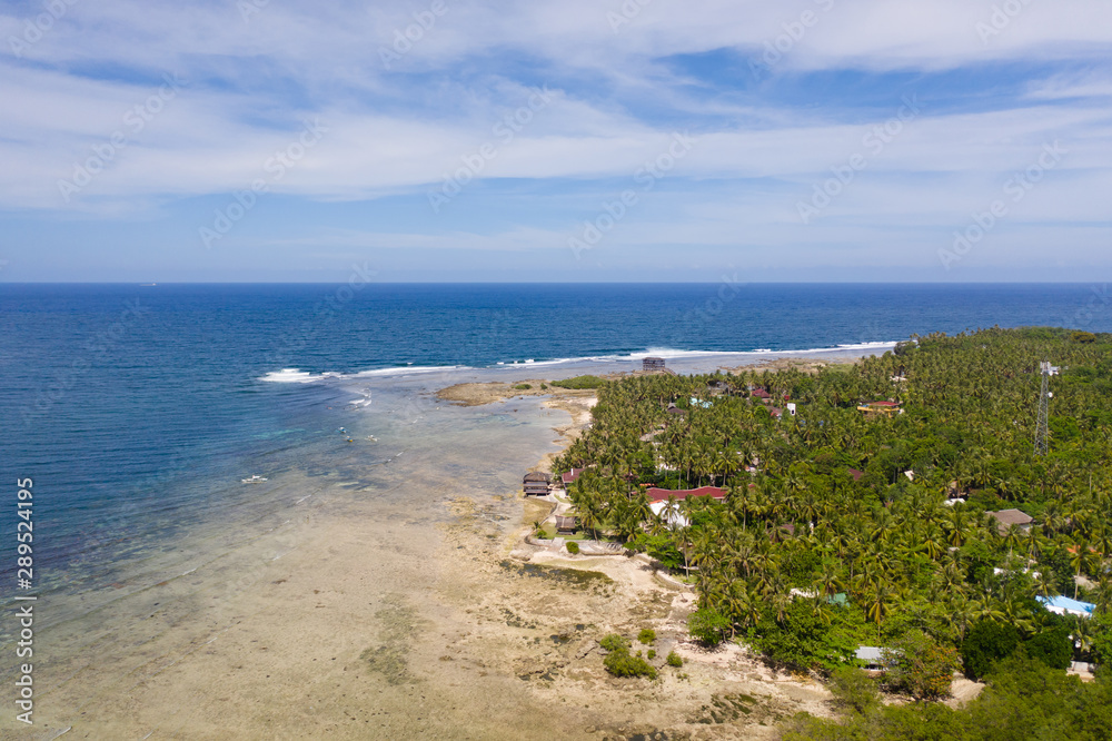 Coast of Siargao Island, Philippines. Landscape with a tropical island in sunny weather, aerial view.