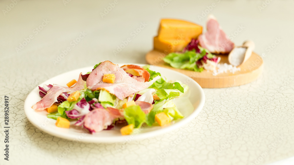 A plate of salad of green leaves, ham and cheese. Plate of salad with green leaves, ham and cheese. Fresh lettuce, cheese, ham and sea salt on a cutting board. Intercontinental breakfast at the hotel. A plate of salad of green leaves, ham and cheese. Plate of salad with green leaves, ham and cheese. Fresh lettuce, cheese, ham and sea salt on a cutting board. Intercontinental breakfast at the hotel.