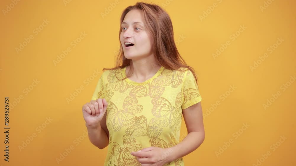 brunette girl in yellow t-shirt over isolated orange background shows emotions brunette girl in yellow t-shirt over isolated orange background shows emotions