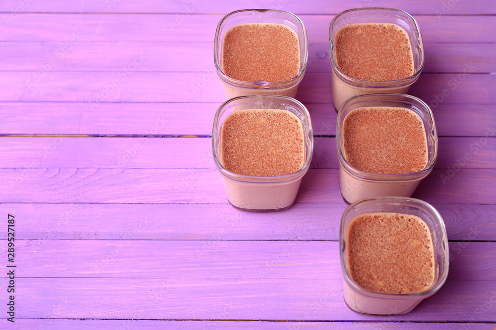 Five portions of chocolate milk dessert are on a wooden table of purple. Breakfast dessert on a violet wooden background. Flat lay. Five portions of chocolate milk dessert are on a wooden table of purple. Breakfast dessert on a violet wooden background. Flat lay.