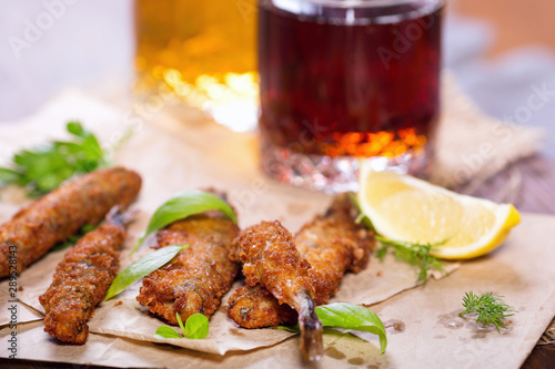 Fried anchovies in batter. Fried fish snack for beer. Mediterranean snack with greens and lemon.