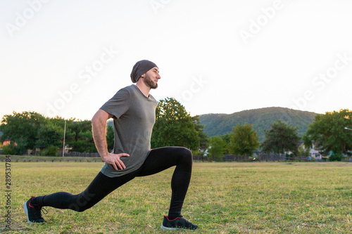 Sports and yoga. A man with a beard, in sportswear squats during a workout. Close up