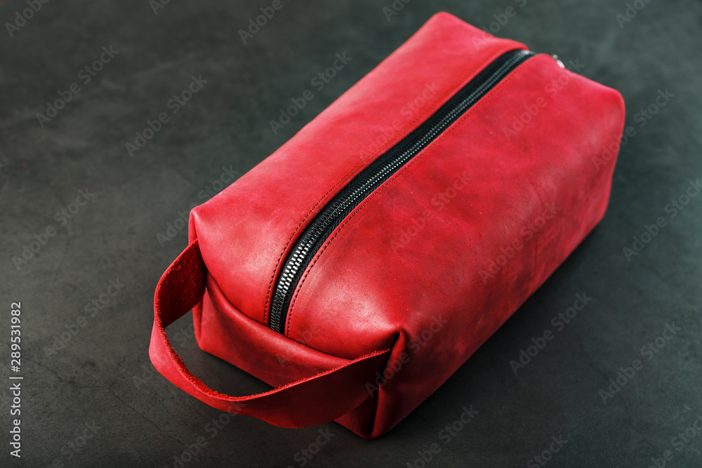 Naklejka premium Bag for cosmetics and jewelry made of genuine red leather, on a dark background. Handwork.