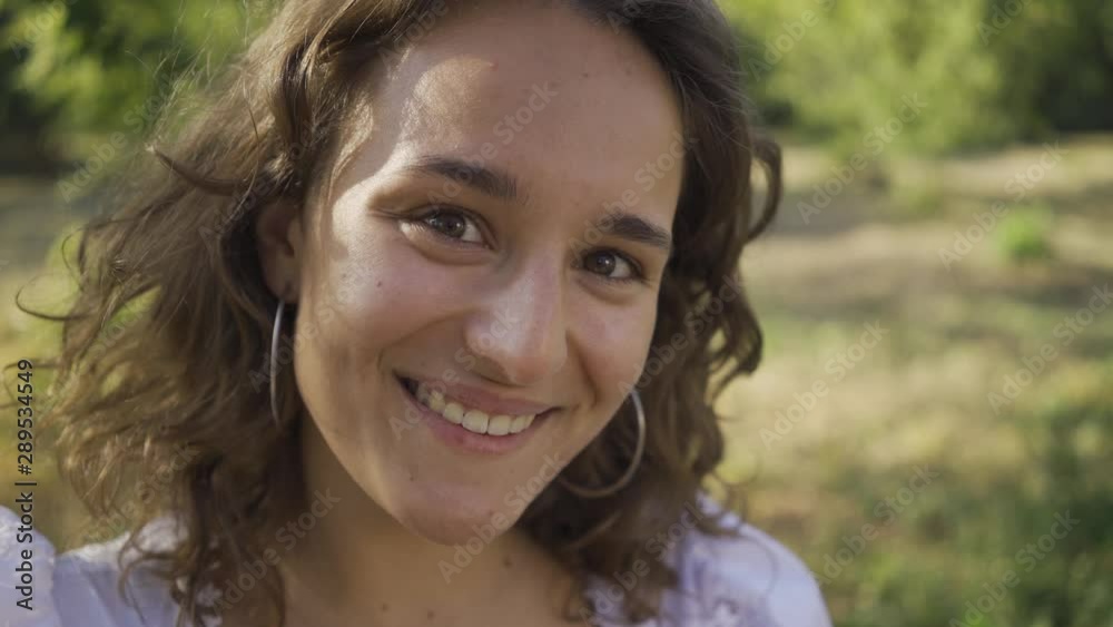 Portrait of positive young woman with curly hair looking at the camera. Rural life. Retro style. Country girl enjoying beautiful summer day Portrait of positive young woman with curly hair looking at the camera. Rural life. Retro style. Country girl enjoying beautiful summer day