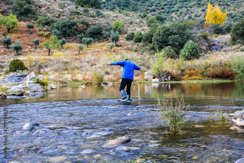 Man crossing the river with a stick