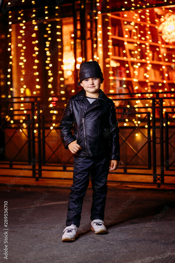 beautiful five year old boy in black leather jacket and bandana on city lights background beautiful five year old boy in black leather jacket and bandana on city lights background