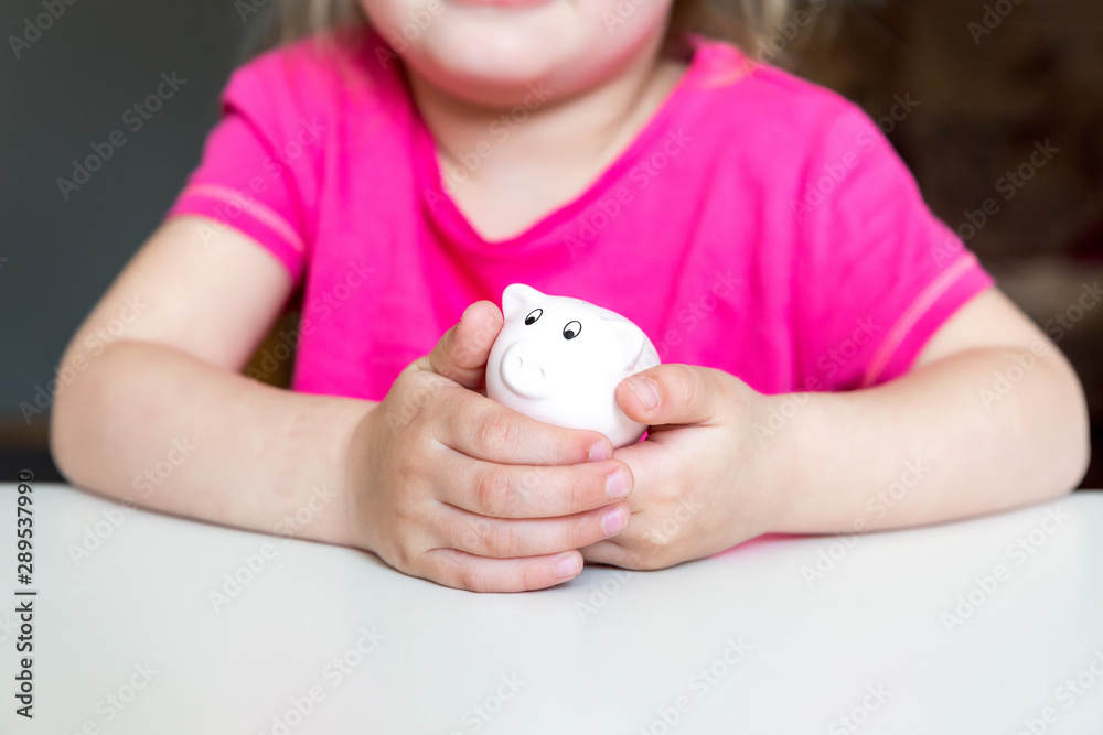 Children hands holding a tiny piggy bank Children hands holding a tiny piggy bank