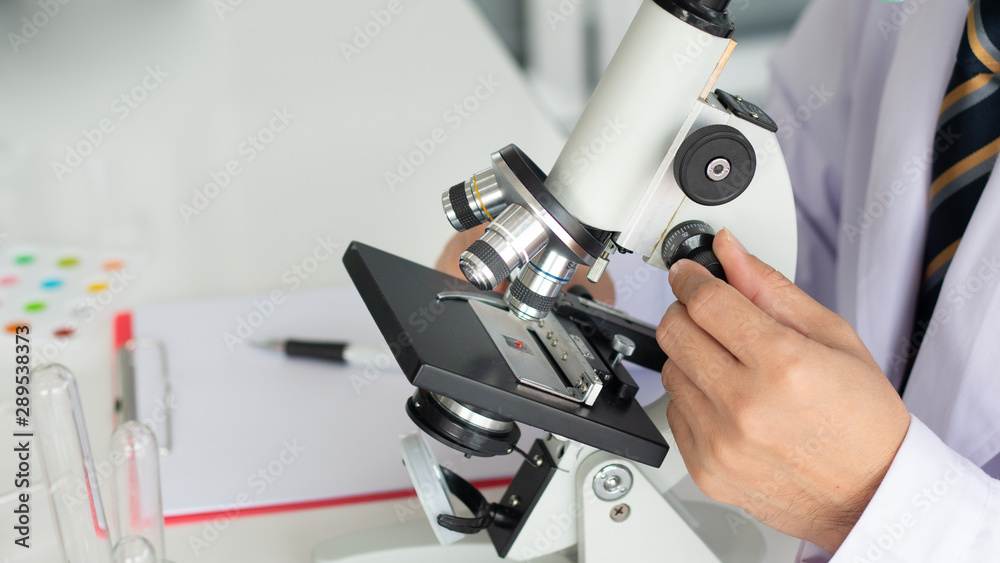scientist look through the microscope in the laboratory. scientist look through the microscope in the laboratory.