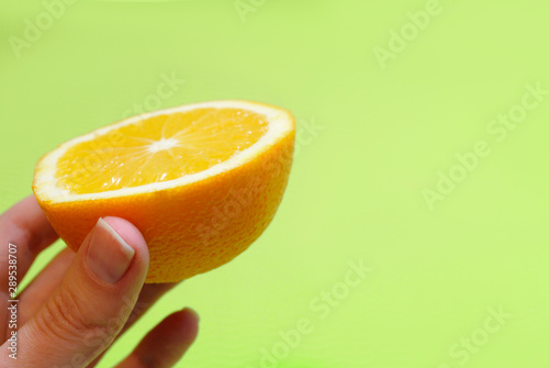 orange in hand on green background