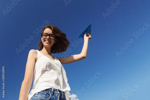 Teenager girl is throwing a paper plane.