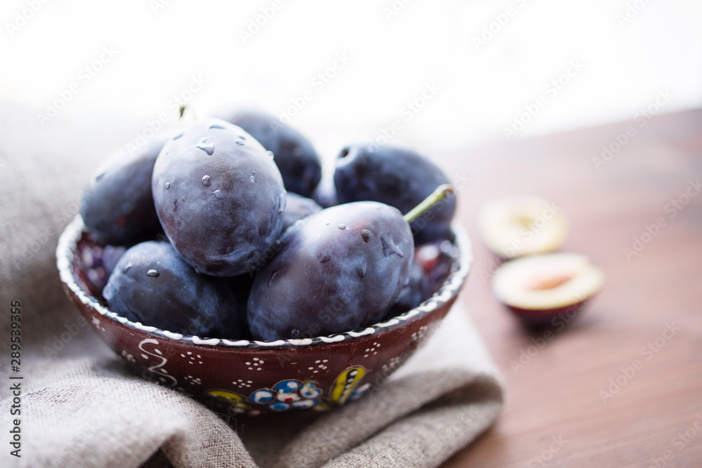 Fresh plums in a bowl on wooden table, soft focus Fresh plums in a bowl on wooden table, soft focus