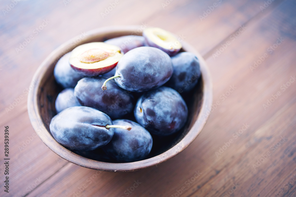 Fresh plums in a bowl on wooden table, soft focus Fresh plums in a bowl on wooden table, soft focus