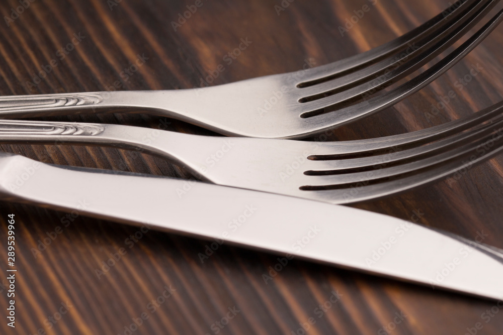 fork and knife on a dark wood table, close up fork and knife on a dark wood table, close up