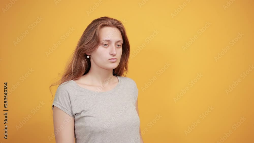 brunette girl in gray t-shirt over isolated orange background shows emotions brunette girl in gray t-shirt over isolated orange background shows emotions