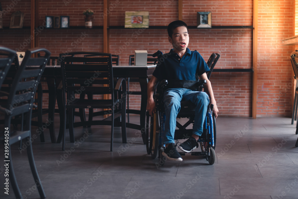 Obraz premium Disabled child on wheelchair play and learn indoors,Vintage style orange brick background,Special children's lifestyle,Life in the education age of special need children,Happy disability kid concept.