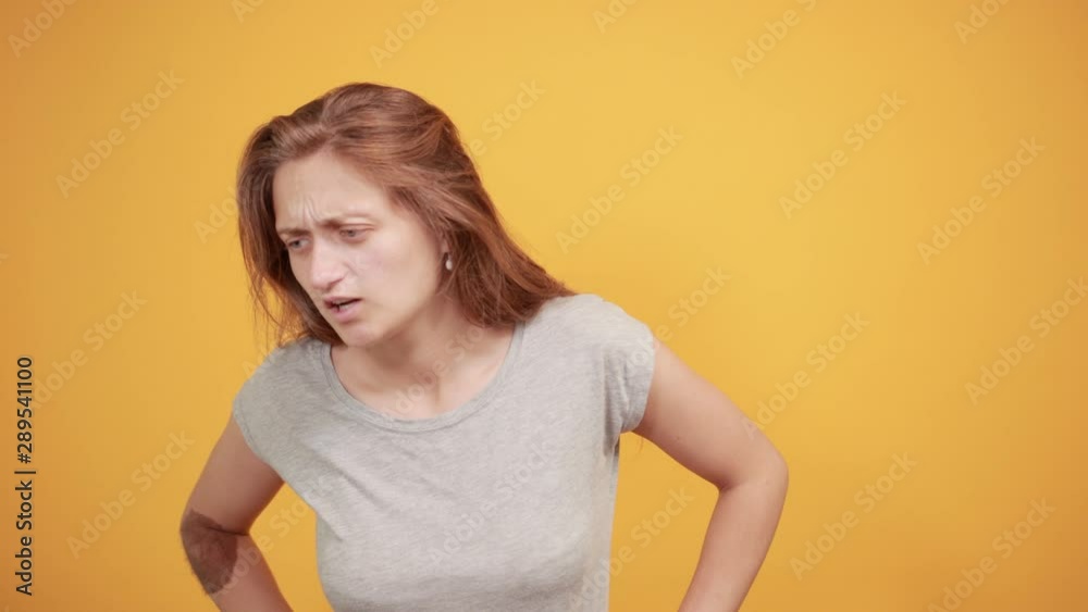 brunette girl in gray t-shirt over isolated orange background shows emotions brunette girl in gray t-shirt over isolated orange background shows emotions