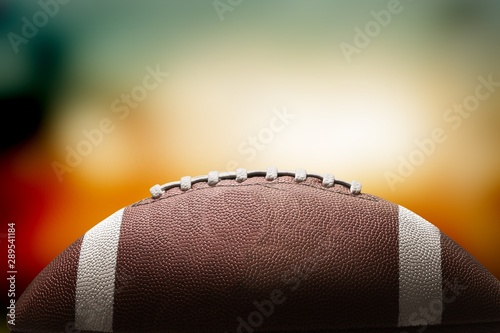 American football ball on black background illuminated by the light