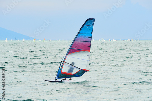 Windsurfing on Lake Garda. Unidentifiable Windsurfer Surfing The Wind On Waves, Recreational Water Sports, Selective focus