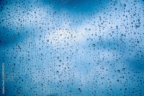 Water drops on glass with overcast sky from the storm. Rain drops on the glass with overcast sky in the rainy season. Can use for add text and abstract background.