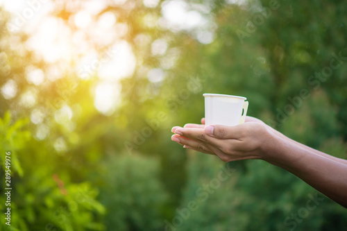 Holding a white glass in the background of natural green leaves