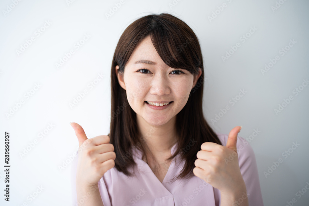 Young business woman showing thumb up gesture against white background Young business woman showing thumb up gesture against white background