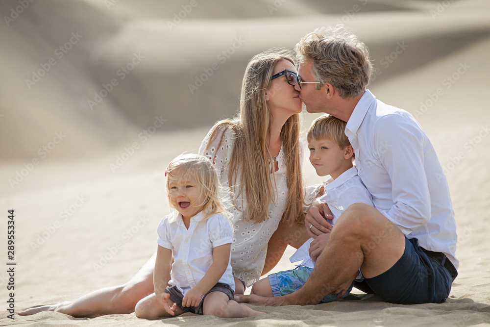 happy family at the beach. Laughing kids. Husband and wife kiss happy family at the beach. Laughing kids. Husband and wife kiss