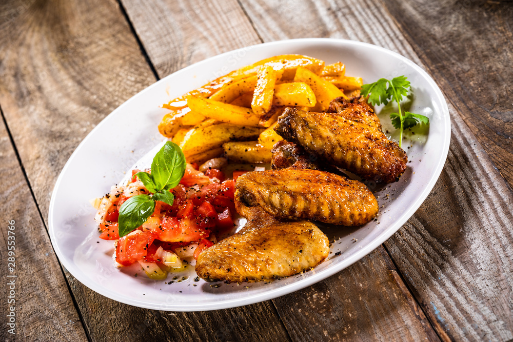 Grilled chicken wings, chips and vegetables Grilled chicken wings, chips and vegetables