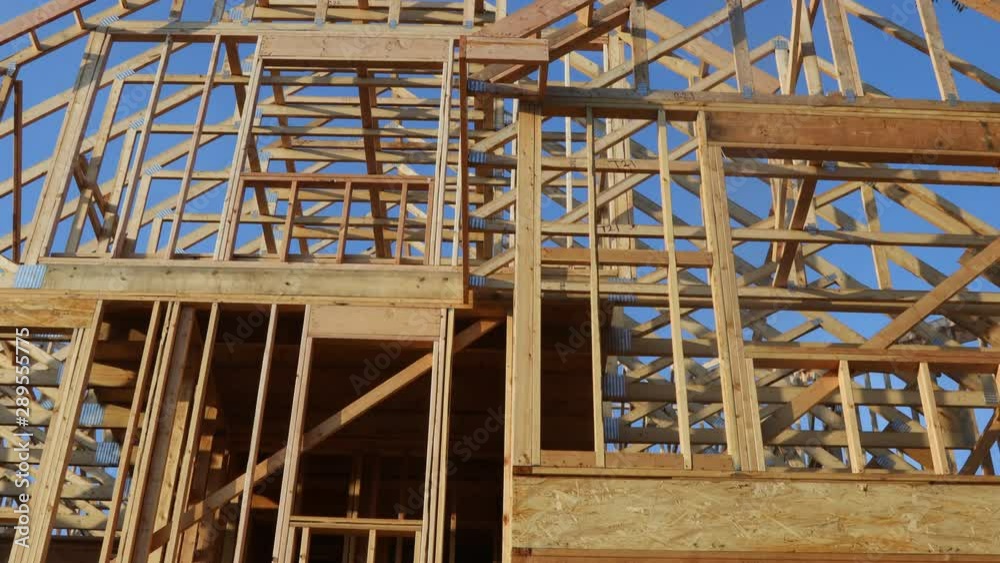 Framing structure wood frame of wooden houses home. Closeup new stick built home under construction under blue sky. Framing structure wood frame of wooden houses home. Closeup new stick built home under construction under blue sky.