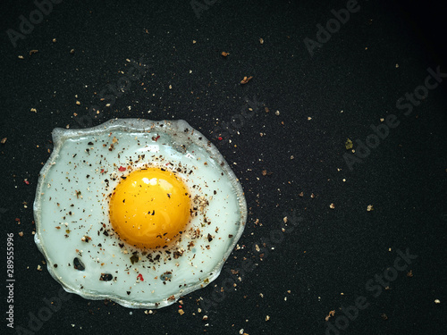 Fried egg. Close up view of the fried egg on a frying pan. Salted and spiced fried egg on cast iron pan.