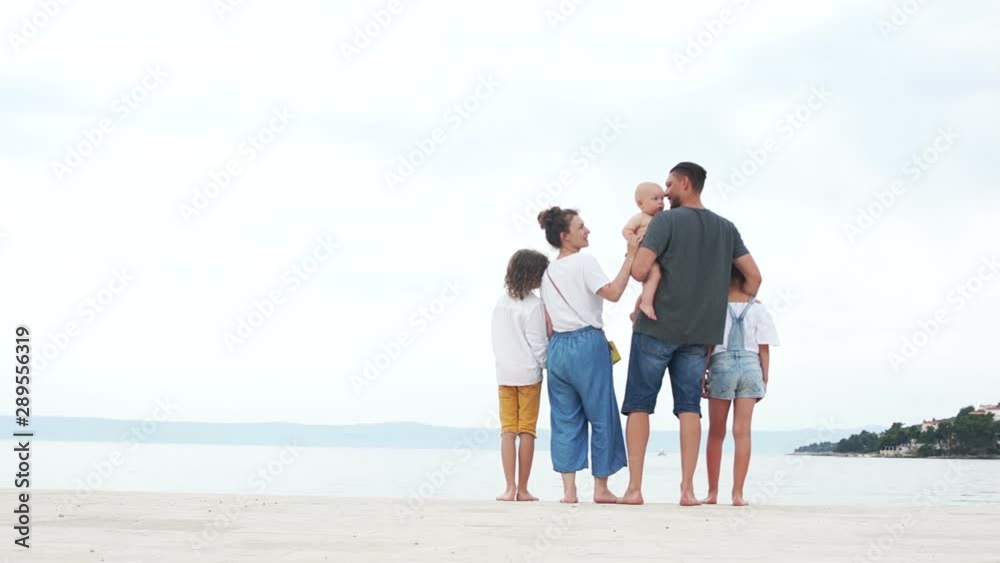Family of five hugging on the beach with white sand. Parents and three children, happy family vacation Family of five hugging on the beach with white sand. Parents and three children, happy family vacation