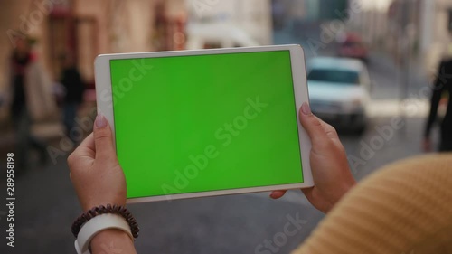 Close up hands woman using tablet device computer with green screen outdoors in street at sunlight horizontal bloom message pad technology chroma key female digital girl app chat finger slow motion